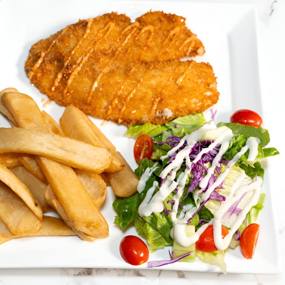 El Cayo's fried fish with fries and a side salad topped with dressing and cherry tomatoes.